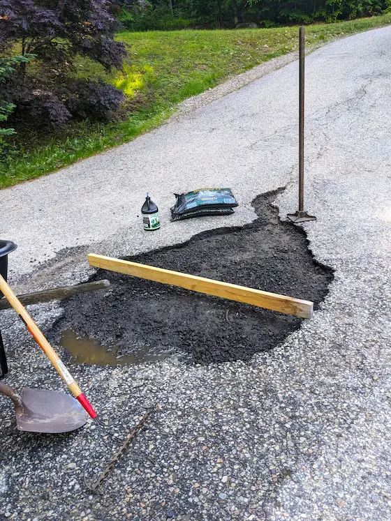 blacktop patch repair in progress tools and wood screed