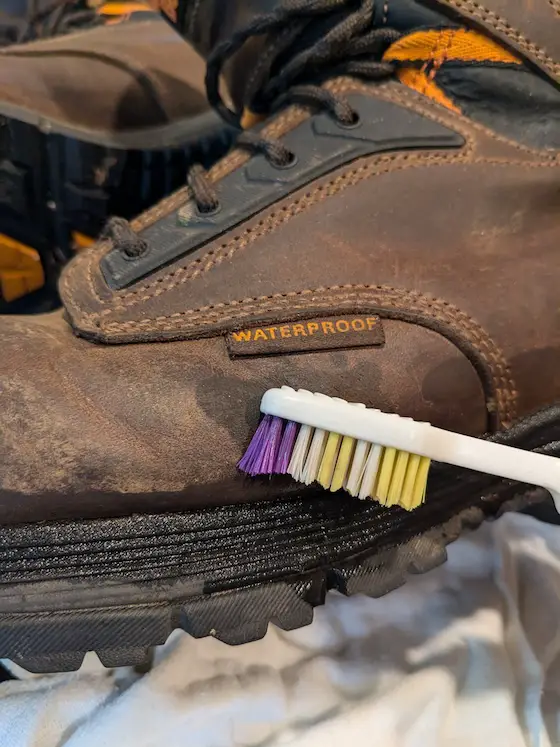 cleaning a leather boot with a toothbrush